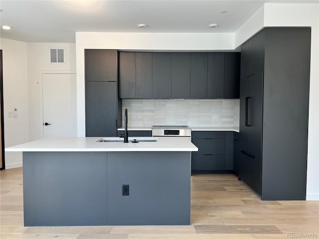 1601 Park Ave Unit 201, Denver, CO 80218 - kitchen featuring modern cabinets, light countertops, tasteful backsplash, an island with sink, and light wood-style flooring