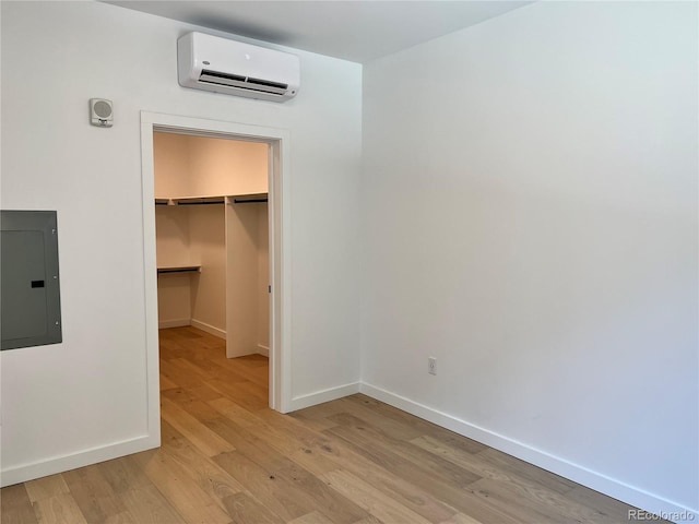 1601 Park Ave Unit 201, Denver, CO 80218 - unfurnished bedroom with a wall mounted air conditioner, electric panel, light wood finished floors, a walk in closet, and a closet