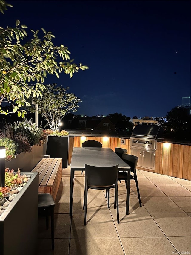1601 Park Ave Unit 201, Denver, CO 80218 - patio at night with outdoor dining area, a patio area, and an outdoor kitchen