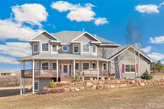 view of front of house with a porch, roof with shingles, and a front yard