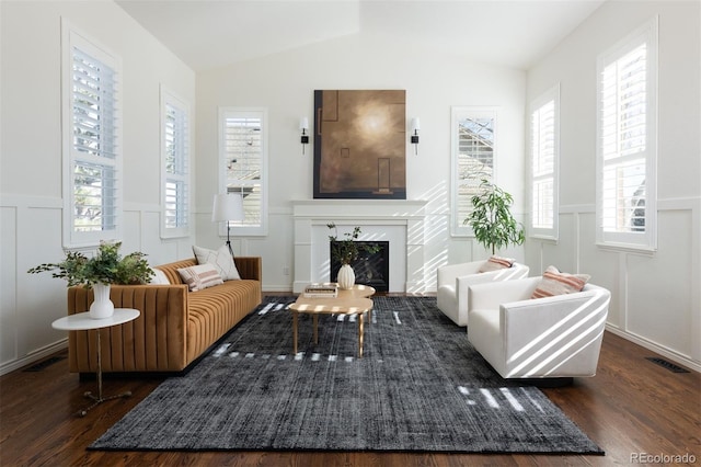 sitting room with dark wood-type flooring, lofted ceiling, a high end fireplace, and a healthy amount of sunlight