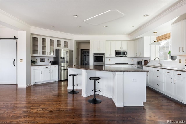 kitchen featuring white cabinets, a barn door, stainless steel appliances, and a center island