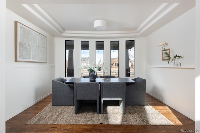 dining area featuring dark wood-type flooring and a raised ceiling