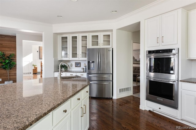 kitchen featuring sink, appliances with stainless steel finishes, white cabinets, and dark stone countertops