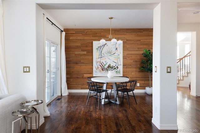 dining room featuring dark wood-type flooring and wooden walls