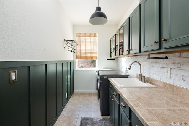 laundry room featuring washing machine and dryer, sink, cabinets, and light tile patterned floors