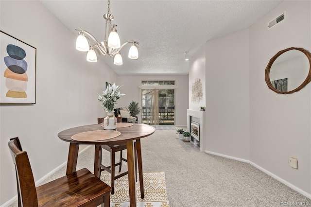 dining space featuring baseboards, visible vents, carpet floors, a fireplace with flush hearth, and a textured ceiling