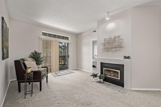 sitting room with visible vents, a fireplace with flush hearth, a textured ceiling, and carpet flooring