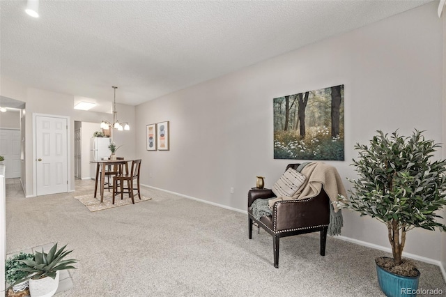 living area with a notable chandelier, carpet flooring, baseboards, and a textured ceiling