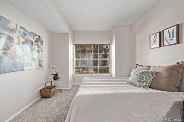 carpeted bedroom featuring baseboards and a textured ceiling