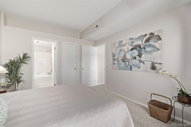 carpeted bedroom with visible vents, ensuite bath, and baseboards