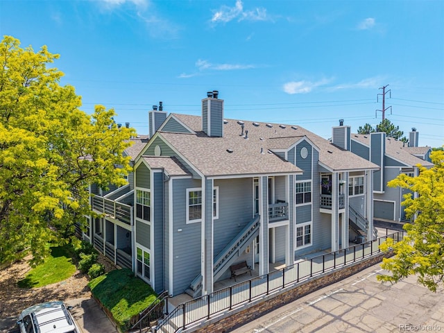 7481 Singing Hills Dr, Boulder, CO 80301 - rear view of house featuring a chimney, a shingled roof, and stairs