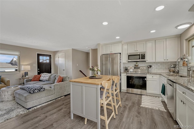 280 Jupiter Dr, Lone Tree, CO 80124 - kitchen with appliances with stainless steel finishes, a sink, light wood-style floors, open floor plan, and recessed lighting