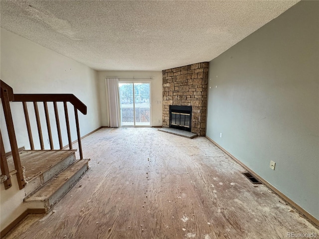 unfurnished living room with a textured ceiling and a stone fireplace