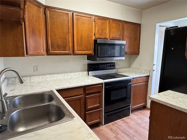 kitchen with light hardwood / wood-style flooring, black range with electric stovetop, and sink