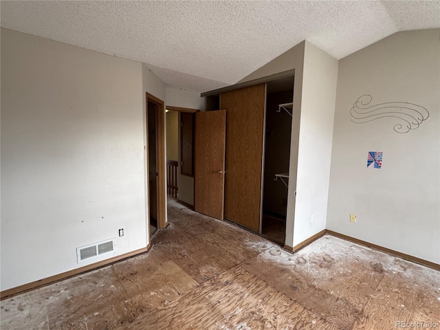 unfurnished bedroom featuring vaulted ceiling, a closet, and a textured ceiling