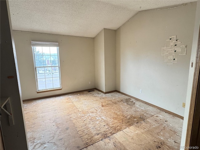 spare room with a textured ceiling and lofted ceiling