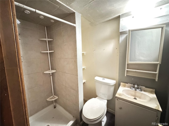 bathroom with toilet, vanity, and a tile shower