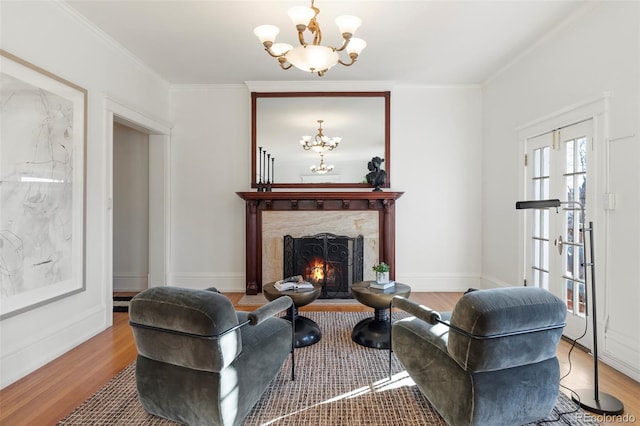 living room featuring a high end fireplace, hardwood / wood-style floors, crown molding, and a notable chandelier