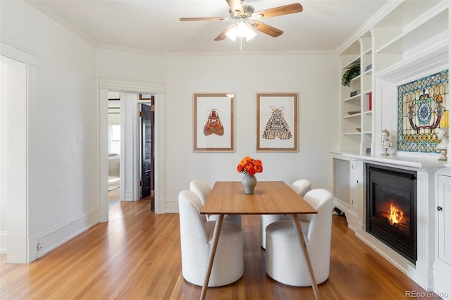 dining area featuring crown molding, built in shelves, ceiling fan, and light hardwood / wood-style flooring