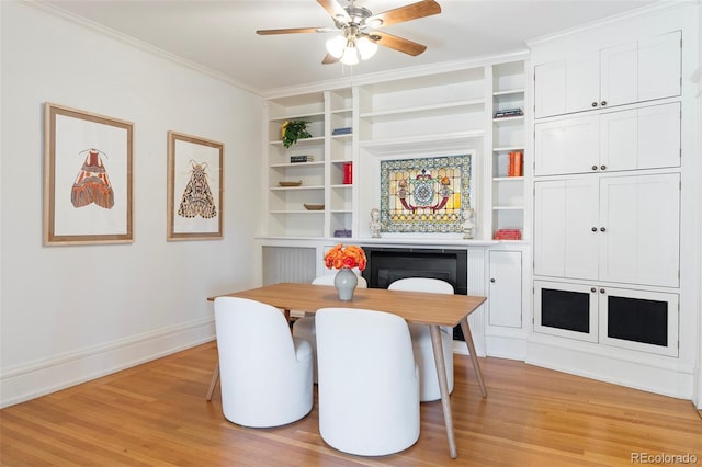 dining space featuring ceiling fan, light wood-type flooring, built in shelves, and crown molding