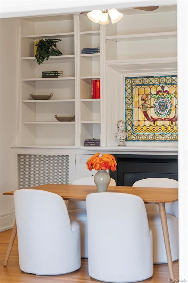 dining area with radiator, light wood-type flooring, and built in shelves