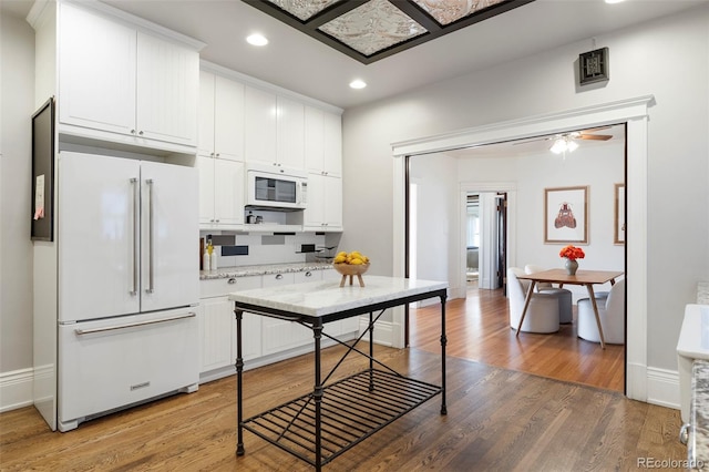 kitchen featuring white cabinetry, light stone counters, white appliances, ceiling fan, and hardwood / wood-style flooring