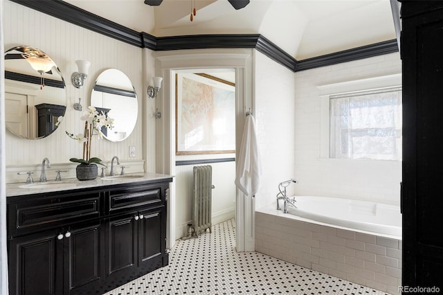 bathroom with vanity, ceiling fan, ornamental molding, radiator, and tiled tub