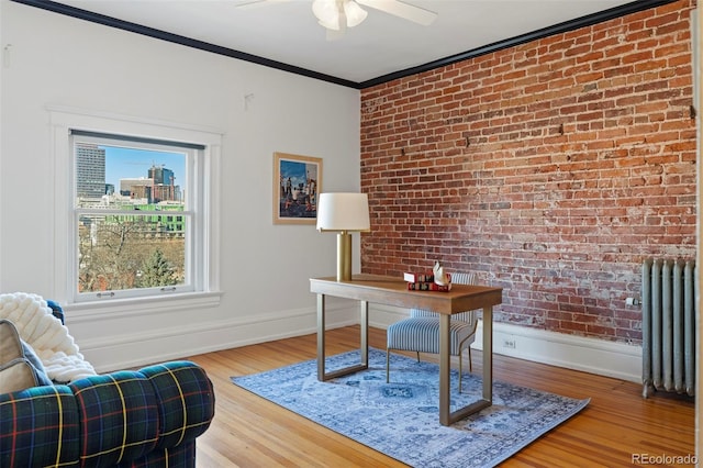 home office featuring brick wall, crown molding, radiator heating unit, and hardwood / wood-style floors