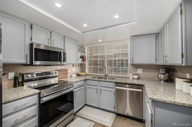 7684 S Monaco Cir, Centennial, CO 80112 - kitchen featuring stainless steel appliances, gray cabinets, decorative backsplash, light stone counters, and a textured ceiling