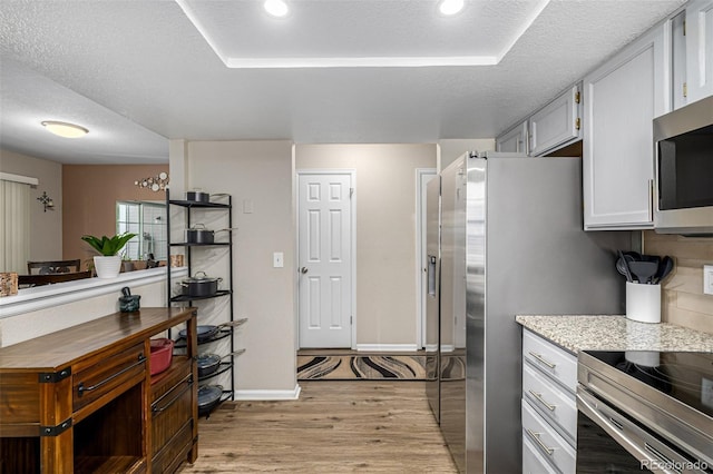7684 S Monaco Cir, Centennial, CO 80112 - kitchen with light wood finished floors, stainless steel appliances, a textured ceiling, recessed lighting, and light stone countertops