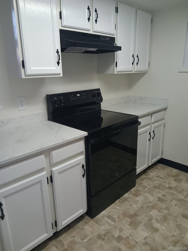 kitchen with light stone counters, under cabinet range hood, electric range, and white cabinetry