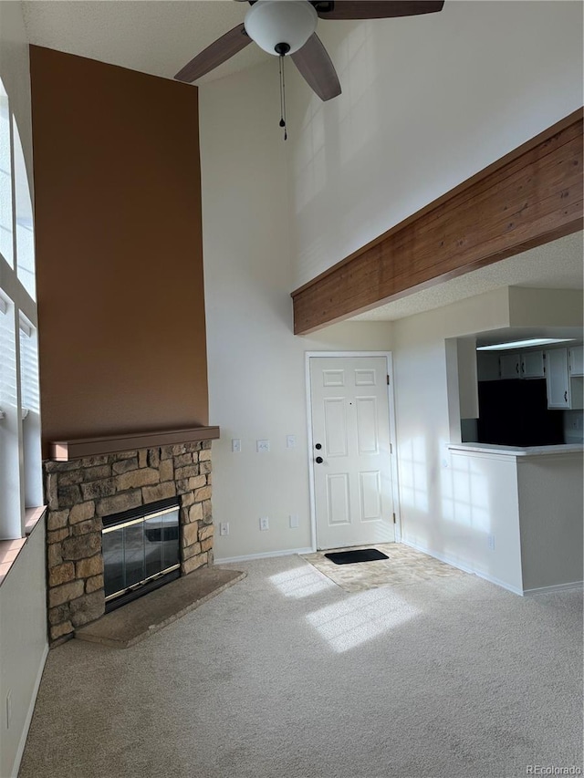 unfurnished living room with a fireplace, baseboards, a high ceiling, a ceiling fan, and carpet