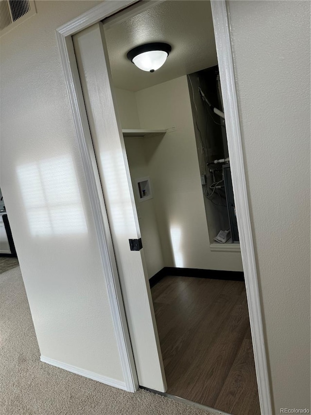 hall featuring baseboards, visible vents, and wood finished floors