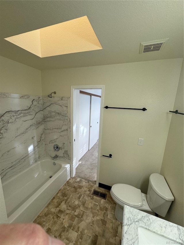 bathroom featuring toilet,  shower combination, visible vents, and a skylight