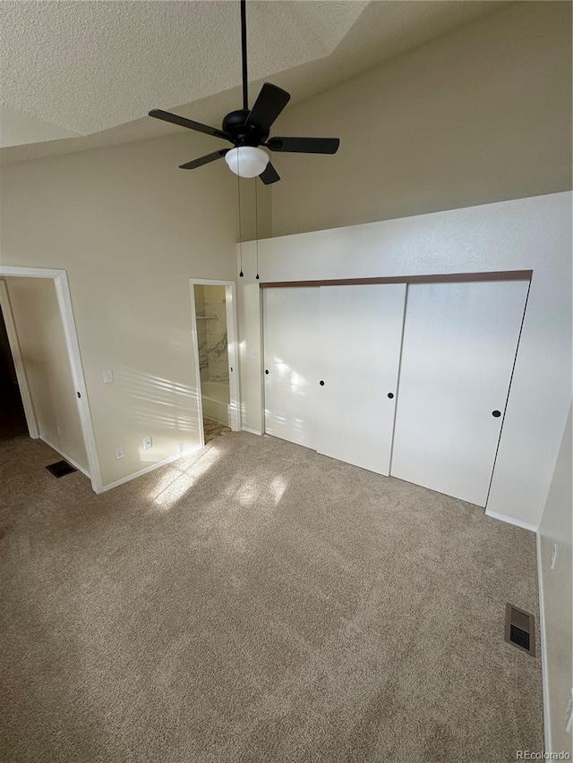 unfurnished bedroom featuring visible vents, carpet flooring, ensuite bath, and high vaulted ceiling