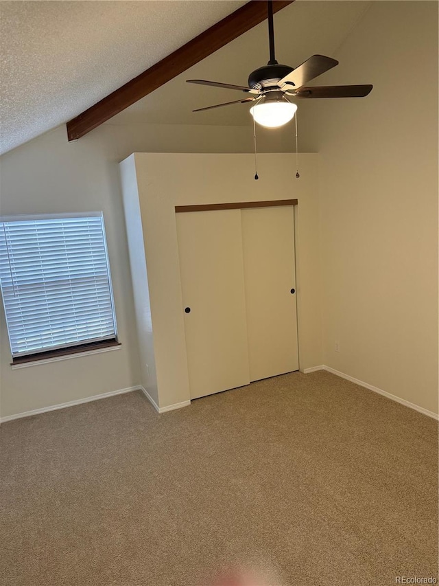 interior space featuring vaulted ceiling with beams, a closet, a textured ceiling, and light colored carpet