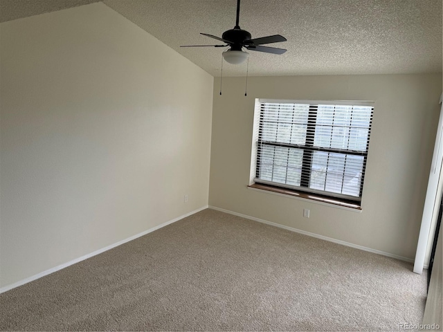 empty room featuring lofted ceiling, baseboards, ceiling fan, a textured ceiling, and carpet