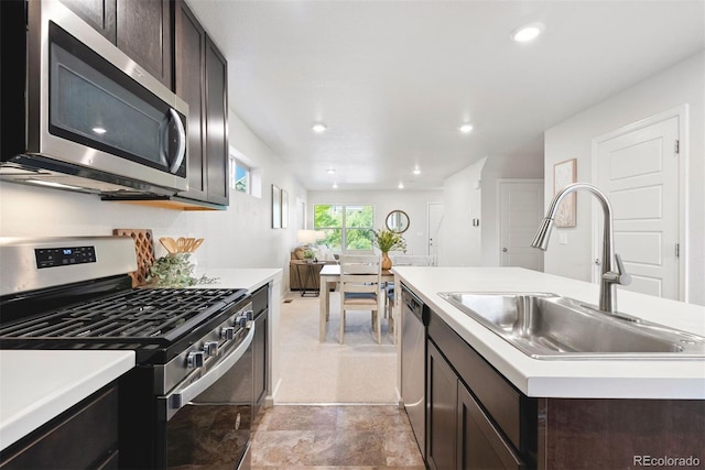 12777 Ulster St, Thornton, CO 80602 - kitchen with appliances with stainless steel finishes, light countertops, dark brown cabinets, an island with sink, and recessed lighting