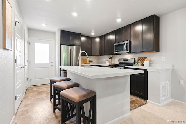 12777 Ulster St, Thornton, CO 80602 - kitchen with appliances with stainless steel finishes, a breakfast bar, light countertops, a center island with sink, and recessed lighting