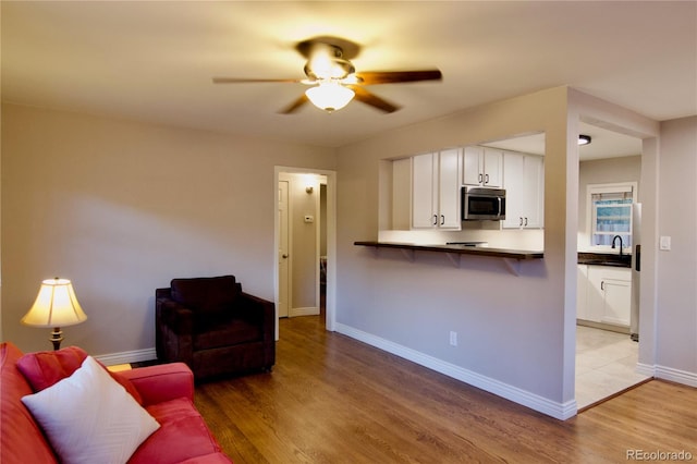 living room featuring ceiling fan, sink, and light hardwood / wood-style flooring