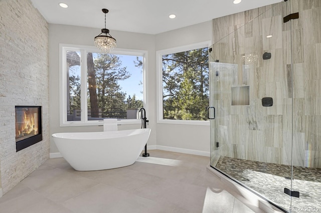 bathroom featuring independent shower and bath, a chandelier, and a fireplace