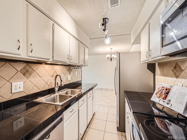 7755 E Quincy Ave Unit 301A7, Denver, CO 80237 - kitchen with appliances with stainless steel finishes, a sink, a textured ceiling, white cabinetry, and light tile patterned floors