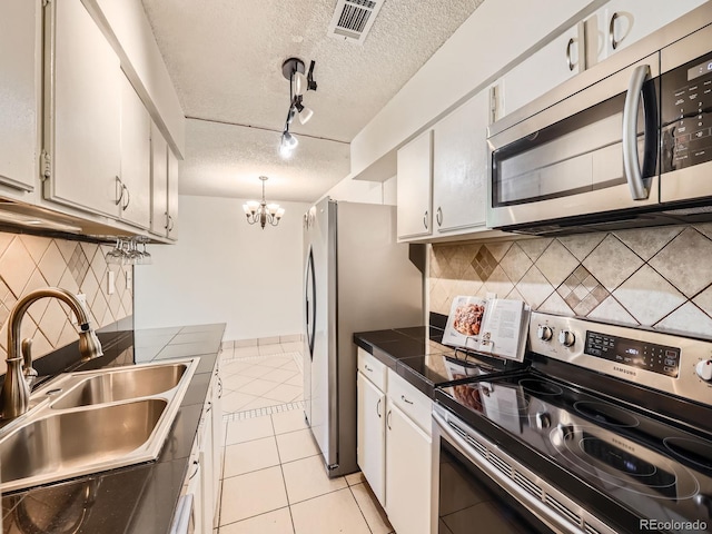 7755 E Quincy Ave Unit 301A7, Denver, CO 80237 - kitchen with stainless steel appliances, a sink, light tile patterned floors, a textured ceiling, and white cabinetry