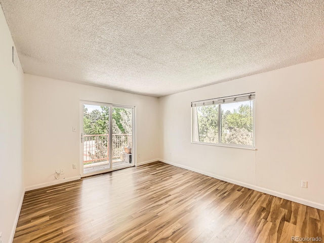7755 E Quincy Ave Unit 301A7, Denver, CO 80237 - unfurnished room with healthy amount of natural light, wood finished floors, a textured ceiling, and baseboards