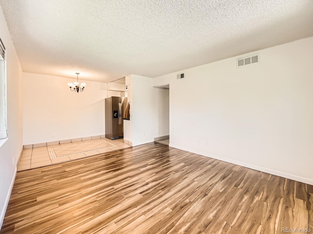 7755 E Quincy Ave Unit 301A7, Denver, CO 80237 - unfurnished room with light wood-style floors, a chandelier, a textured ceiling, and baseboards