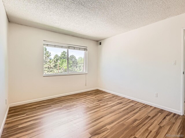 7755 E Quincy Ave Unit 301A7, Denver, CO 80237 - unfurnished room featuring wood finished floors, a textured ceiling, and baseboards