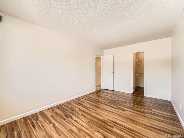 7755 E Quincy Ave Unit 301A7, Denver, CO 80237 - unfurnished bedroom with wood finished floors, baseboards, a textured ceiling, a spacious closet, and a closet