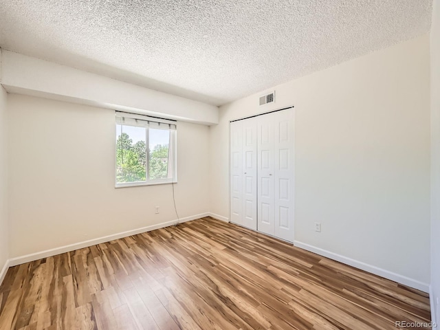 7755 E Quincy Ave Unit 301A7, Denver, CO 80237 - unfurnished bedroom with a closet, wood finished floors, a textured ceiling, and baseboards