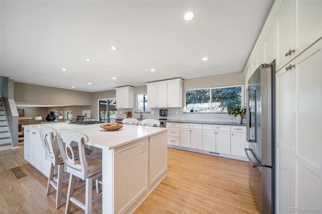 5404 W Rowland Pl, Littleton, CO 80128 - kitchen with stainless steel appliances, a center island, white cabinetry, light wood finished floors, and recessed lighting